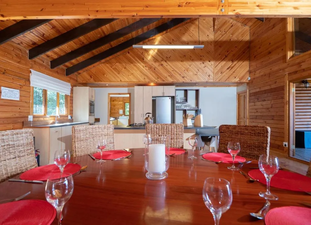 Spacious wooden dining room with set table and open kitchen beyond