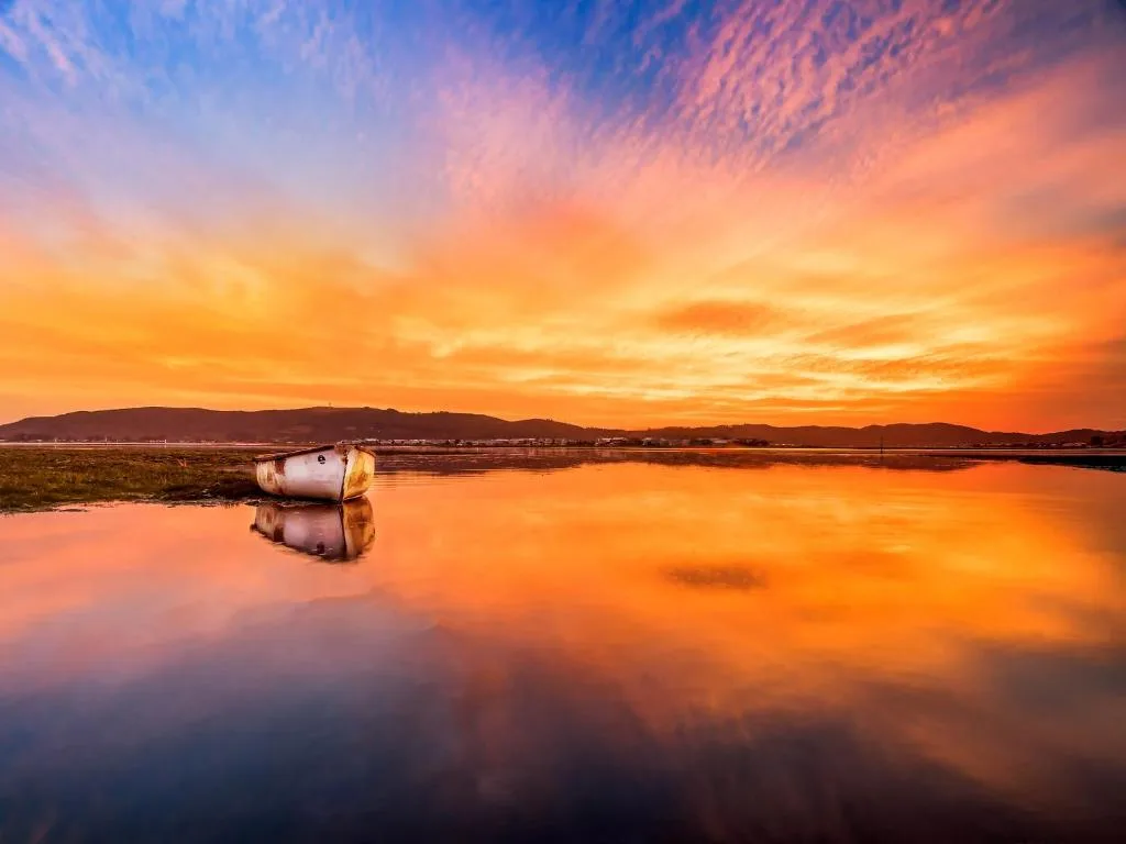 Stunning sunset over Knysna lagoon with moored boat and mountains