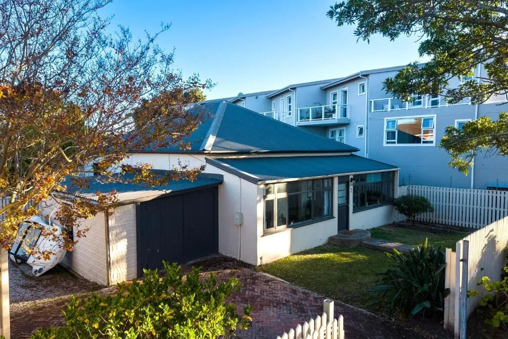 Modern blue and white house exterior with manicured garden and white fence