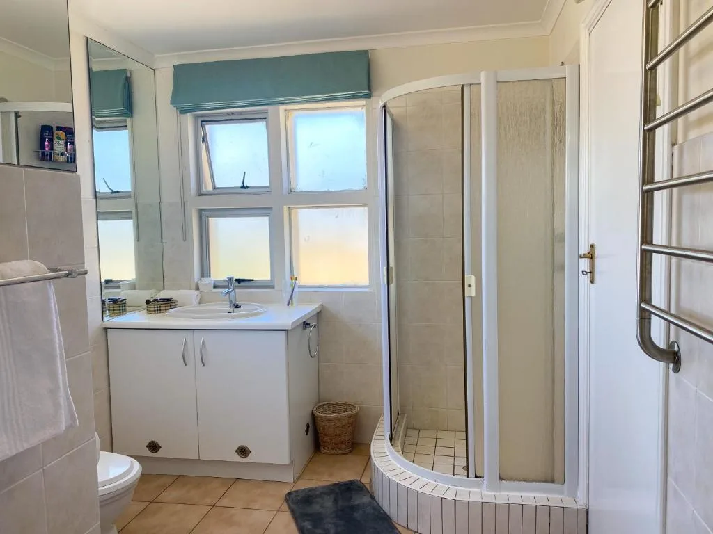 Bright bathroom with curved shower enclosure, white vanity, and window views
