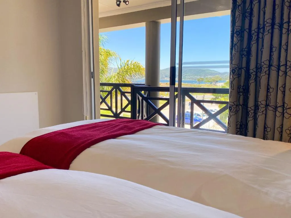 Bedroom with coastal lagoon views through glass doors and balcony