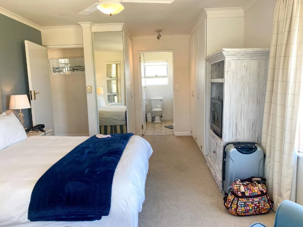 Spacious bedroom with white bed, blue throw, ensuite bathroom visible