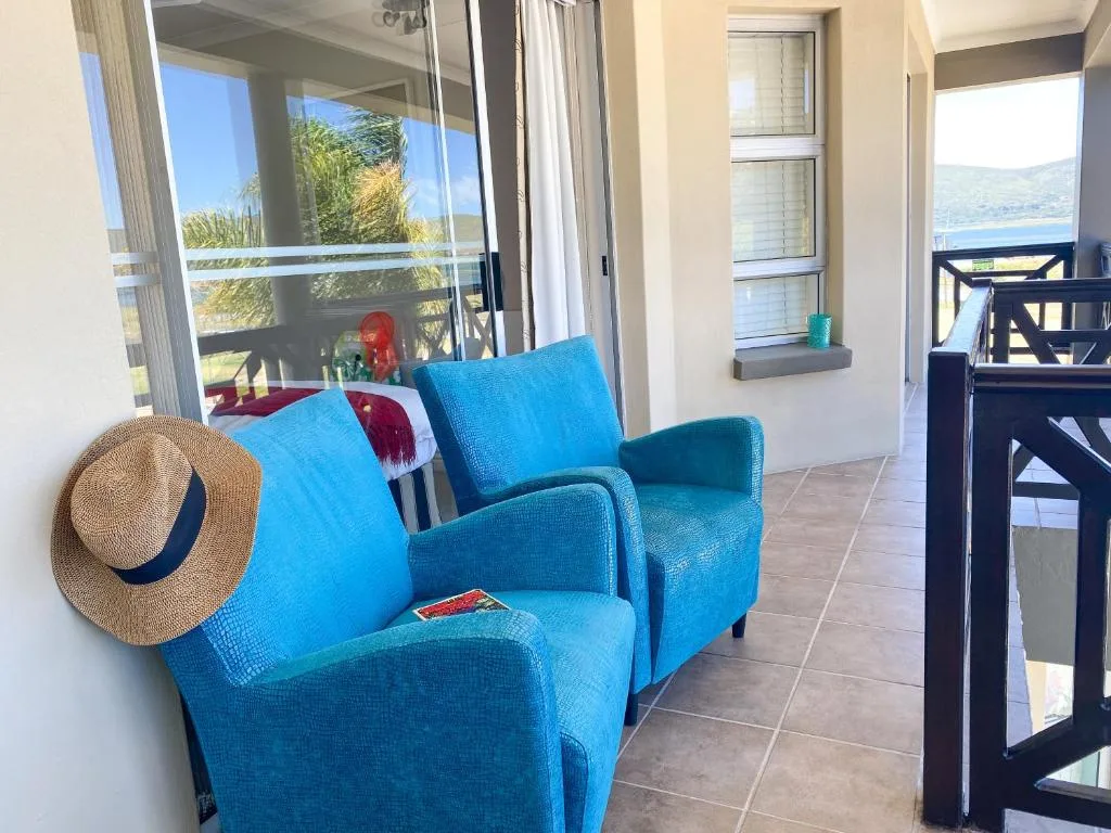 Bright blue armchairs on a spacious patio overlooking water and hills