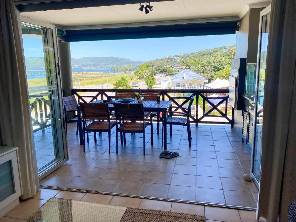Spacious covered deck with dining table overlooking Knysna lagoon and mountains