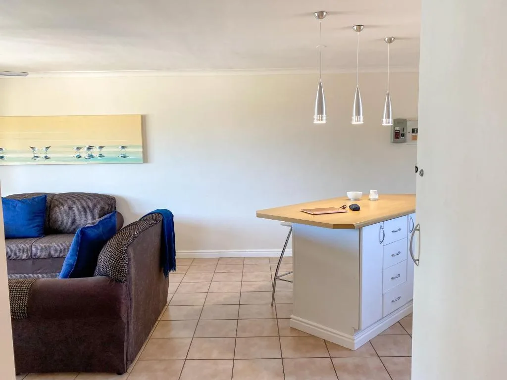 Open-plan lounge and kitchen with sofa, island counter, and pendant lighting