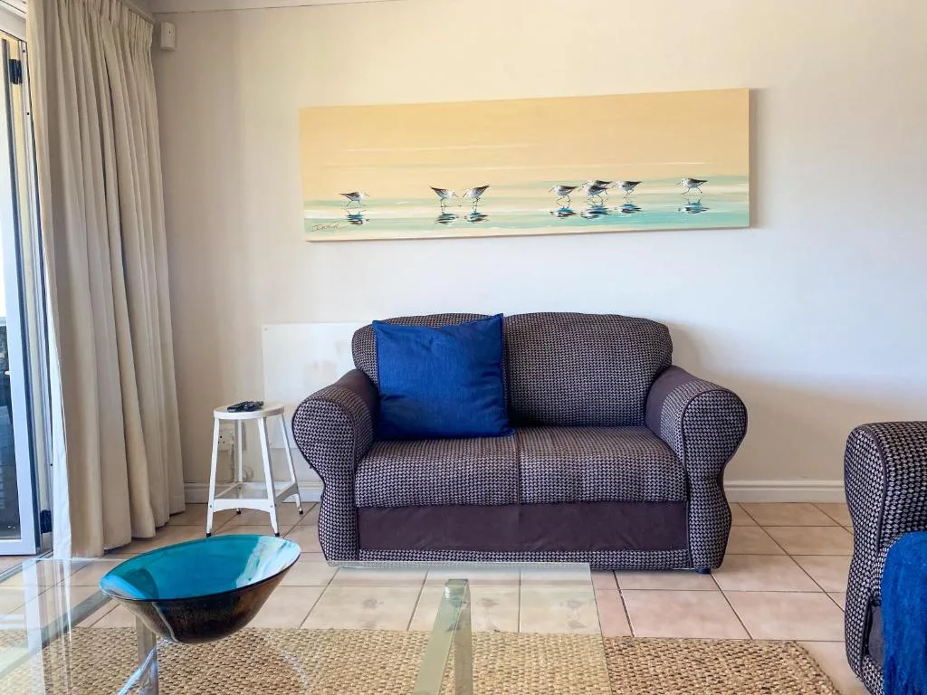 Comfortable gray upholstered sofa with blue cushion in bright living room