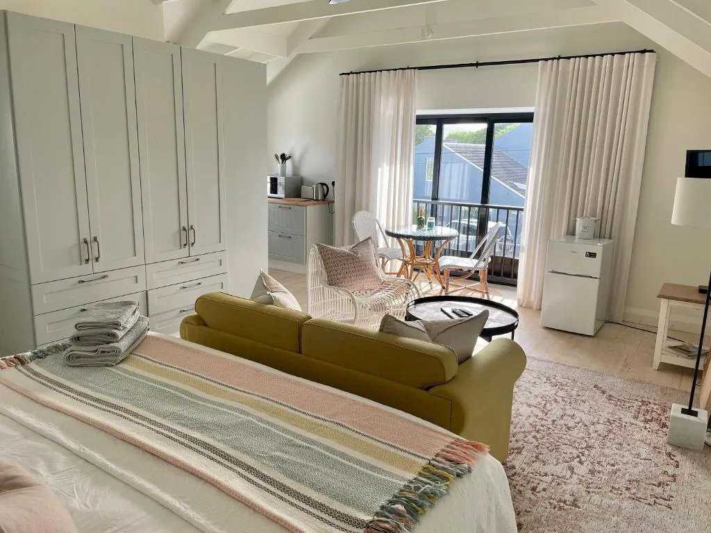 Spacious bedroom with olive sofa, built-in wardrobes, and ocean view doors