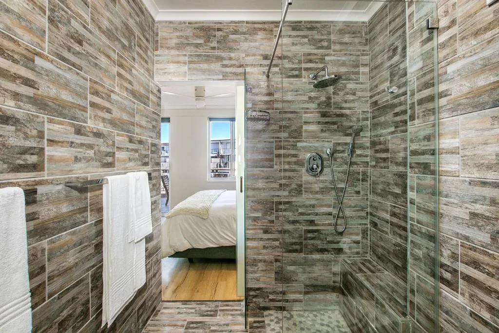 Modern bathroom with wood-grain tile walls and glass shower enclosure