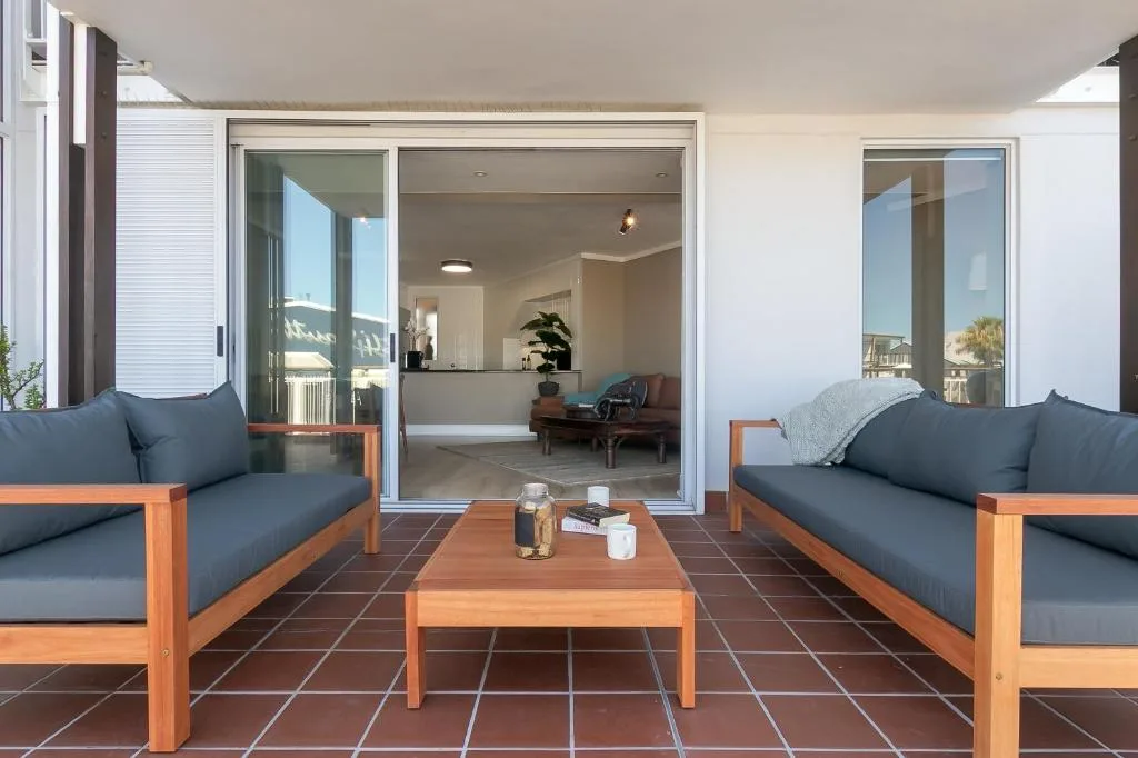 Outdoor patio with wooden furniture and sliding glass doors to lounge