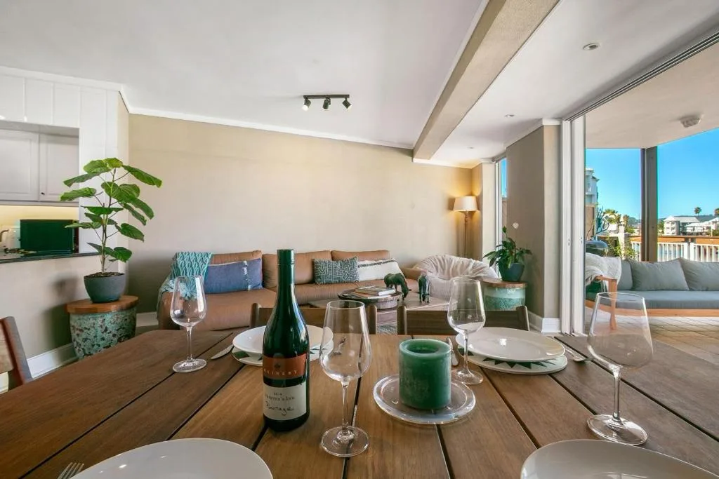 Dining table set for dinner with wine bottle, lounge area and views beyond