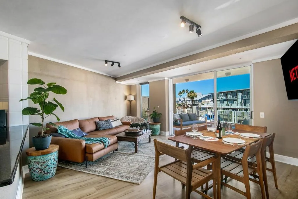 Modern living room with brown leather sofa and dining table with ocean view