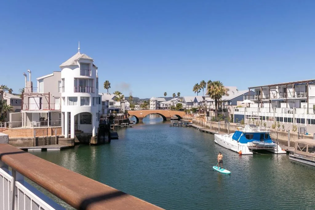 Knysna lagoon waterfront with boats, bridge, and colorful buildings