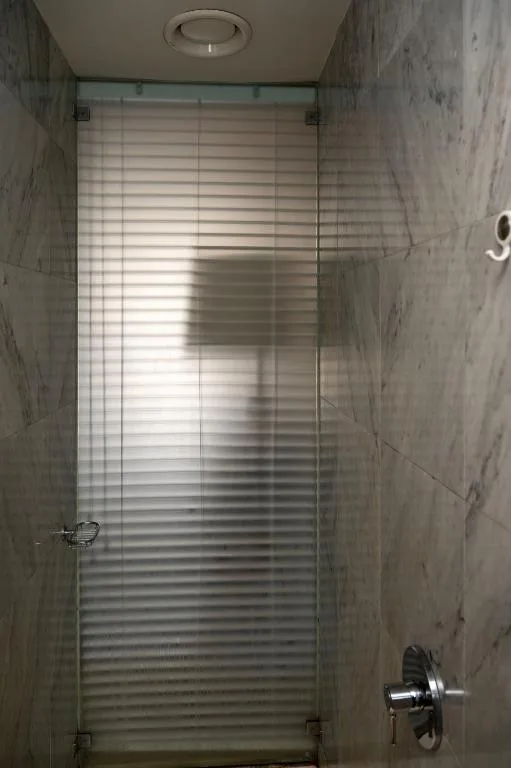 Modern shower enclosure with frosted glass door and gray tile walls