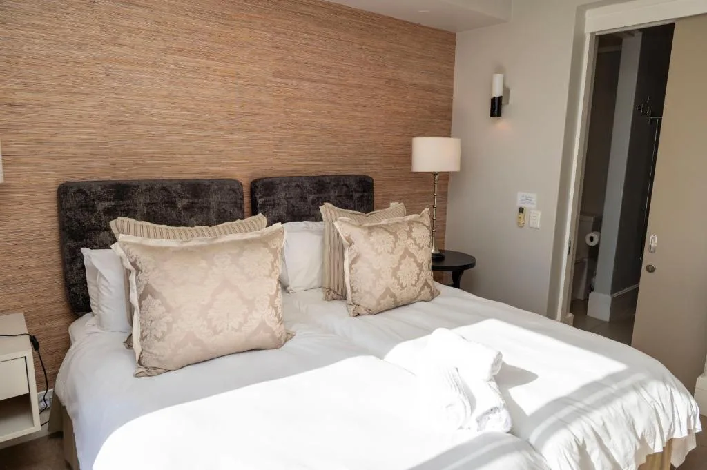 Bedroom with textured headboard, decorative pillows, and bedside lamp