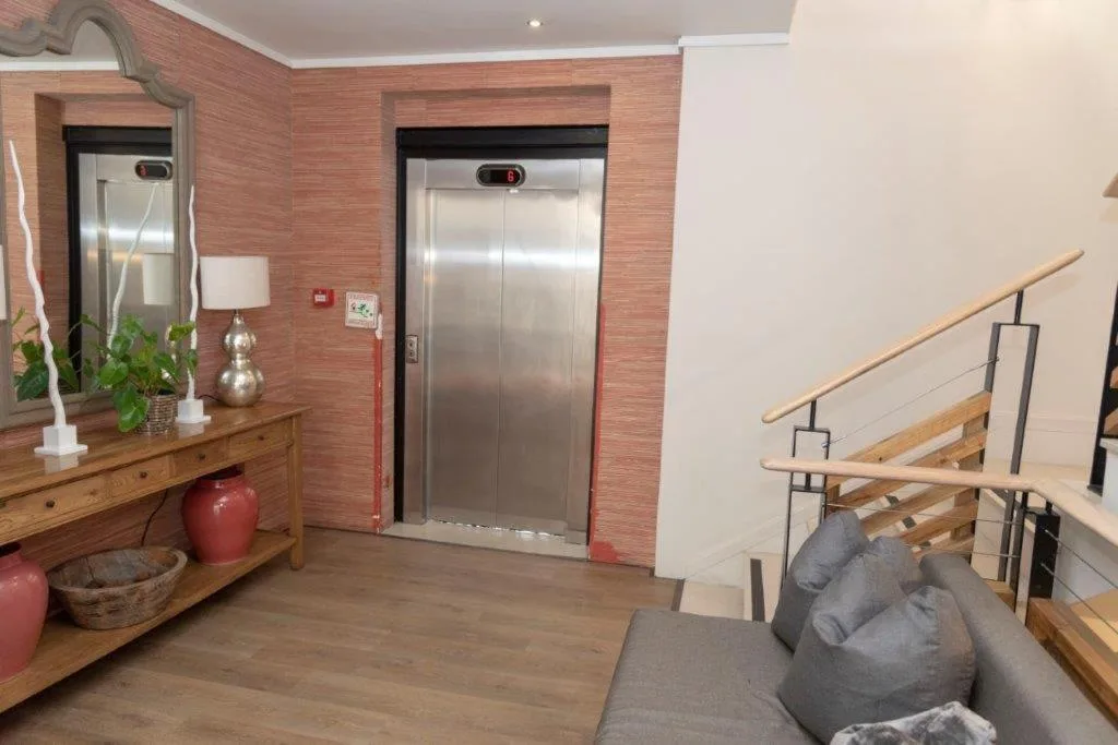 Modern apartment foyer with elevator, wooden console, and staircase access