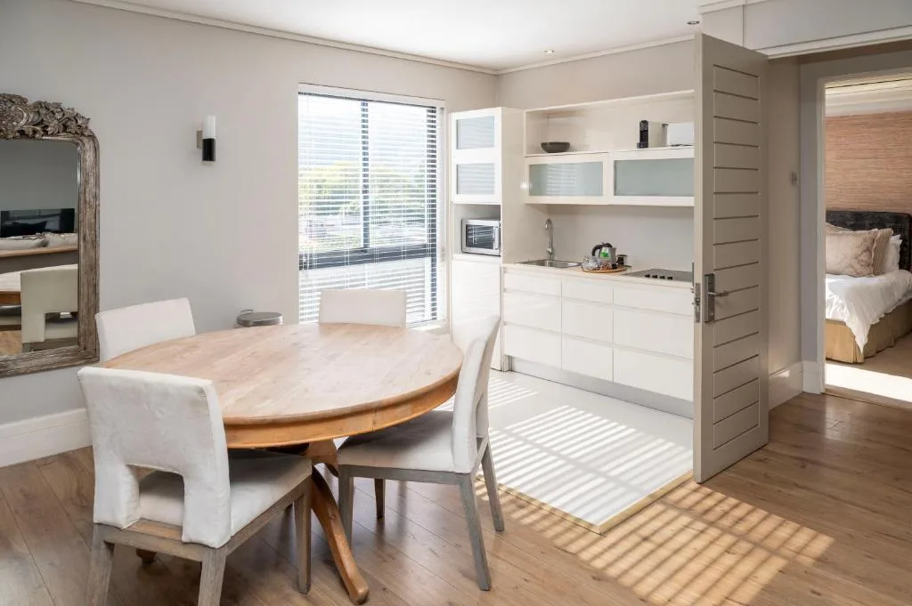 Open-plan dining area with round wooden table and white chairs