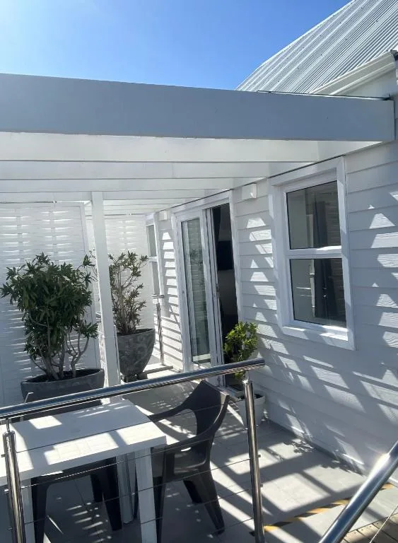 Modern white covered patio with dining table and potted plants