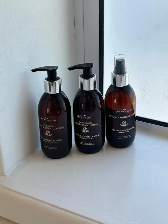 Three luxury amenity bottles displayed on a white windowsill ledge