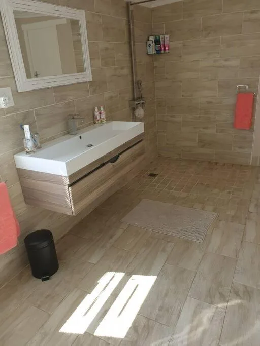 Modern bathroom with vanity sink, mirror, walk-in shower, and tiled flooring