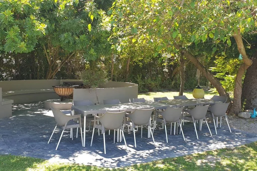 Outdoor dining area with table, chairs, and mature trees providing shade
