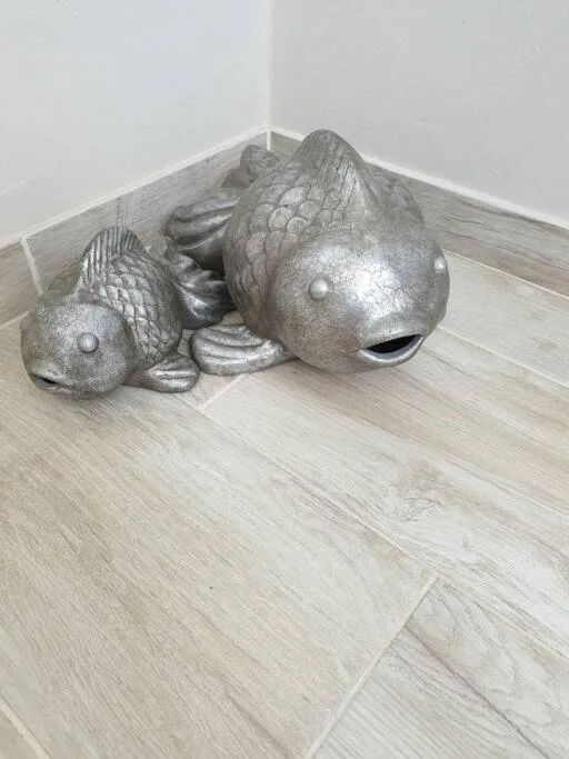 Decorative silver fish sculptures displayed on wooden floor