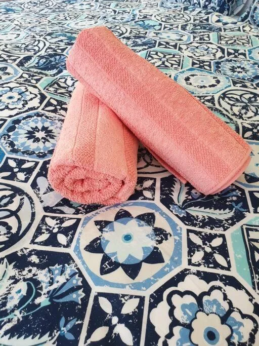Pink rolled towels displayed on decorative blue and white patterned tiles