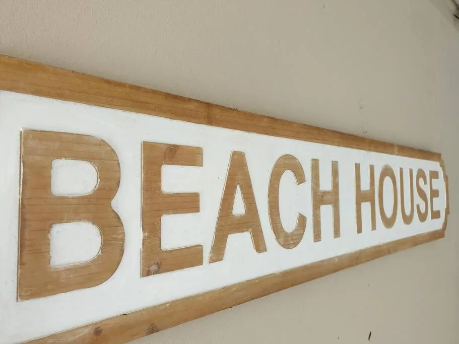 Wooden beach house sign with carved letters on white background
