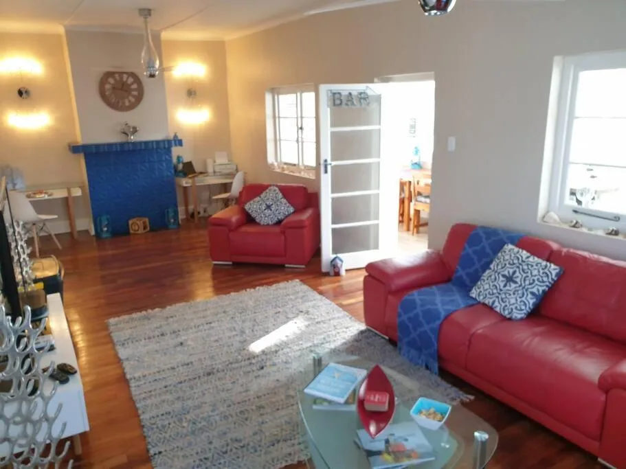 Spacious living room with red sofas, wooden floors, and bright natural light