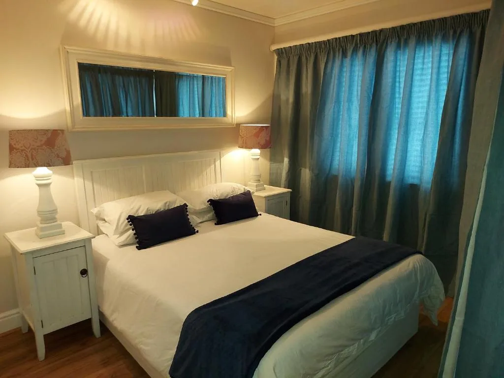 Bright bedroom with queen bed, white bedside tables, and blue curtains