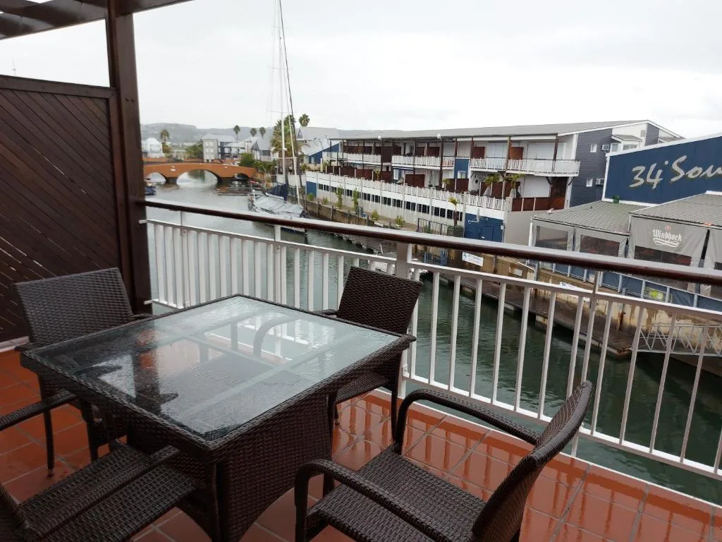 Waterfront balcony with dining table overlooking Knysna lagoon and bridge