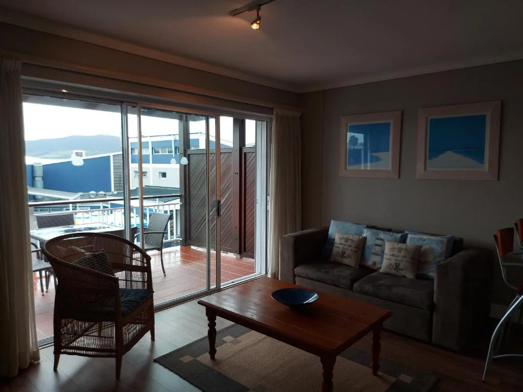 Open-plan lounge with sofa, wicker chair, coffee table, and ocean views