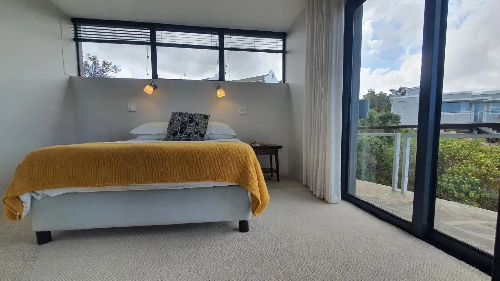 Modern bedroom with mustard throw, pendant lights, and glass doors to deck
