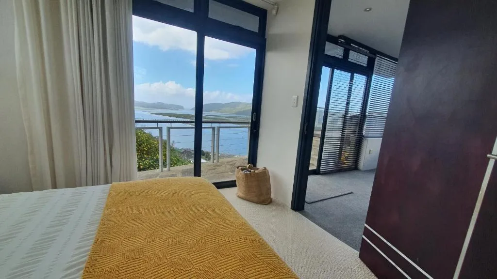 Bedroom with bed and lagoon view through large sliding glass doors