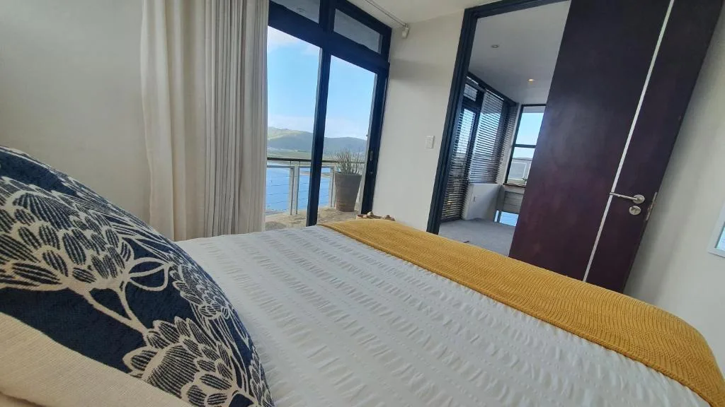 Bedroom with water view through glass doors and modern furnishings
