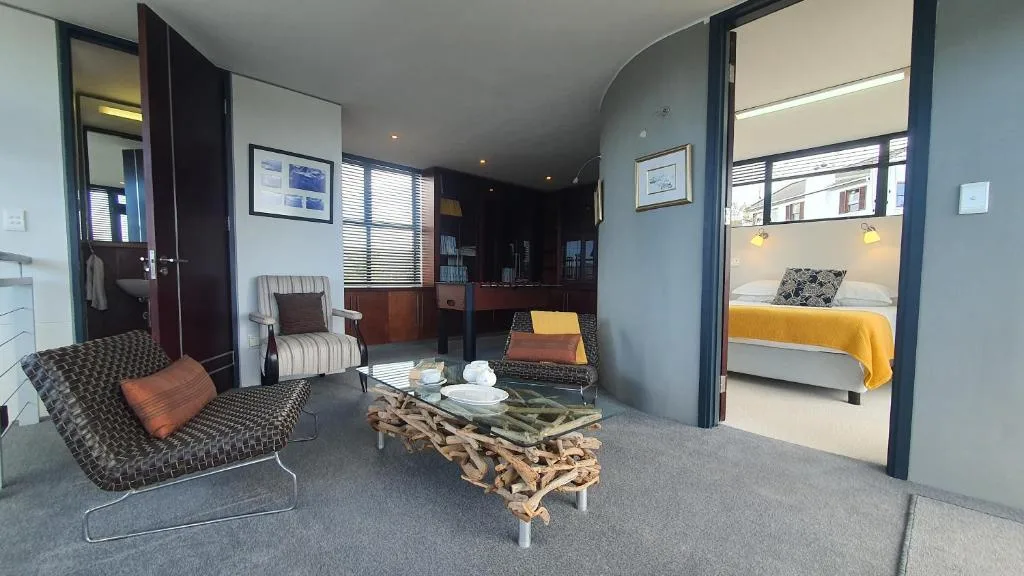 Modern lounge with patterned seating, driftwood coffee table, and bedroom access