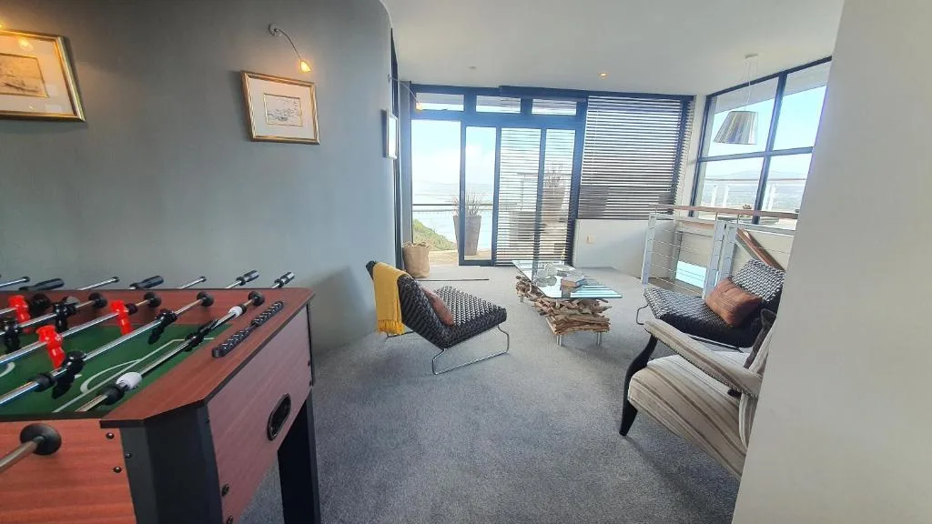 Recreational lounge with foosball table, seating, and panoramic windows overlooking ocean