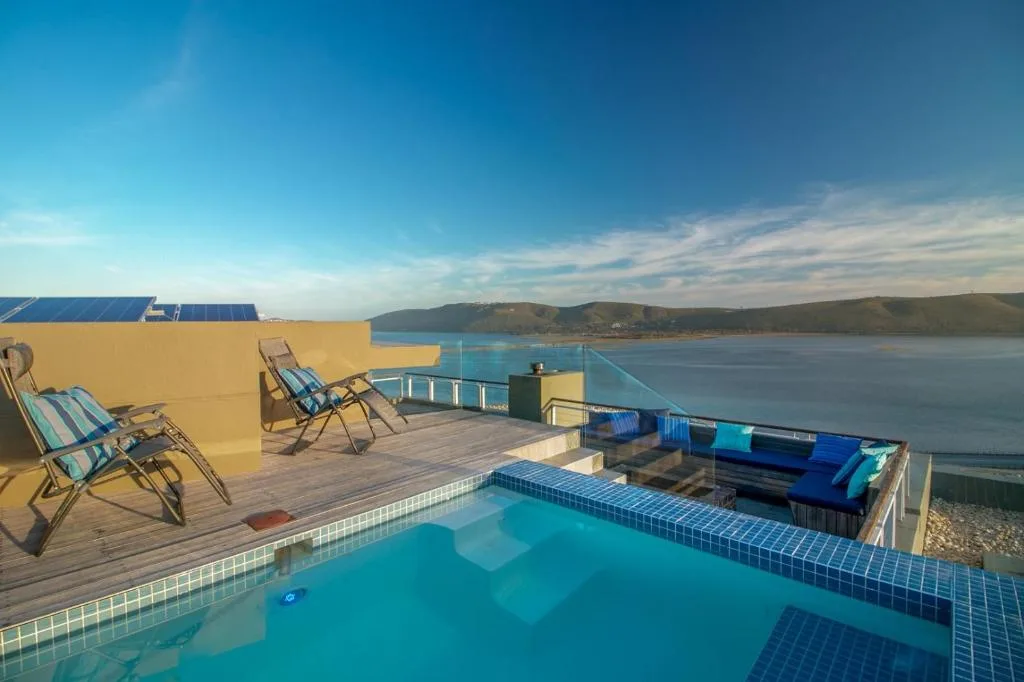 Turquoise swimming pool on wooden deck with lagoon views and loungers
