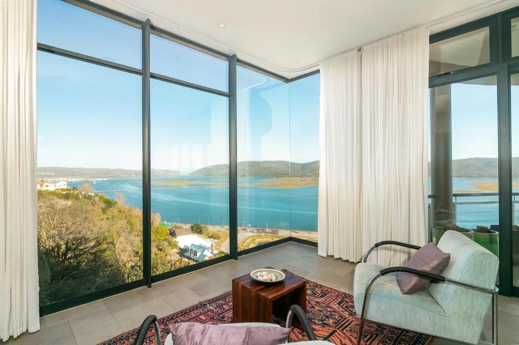 Panoramic coastal view of turquoise lagoon and mountains through floor-to-ceiling windows