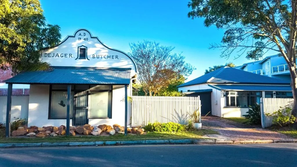 Historic 1940 De Jager Butcher building with white corrugated iron fence and gardens