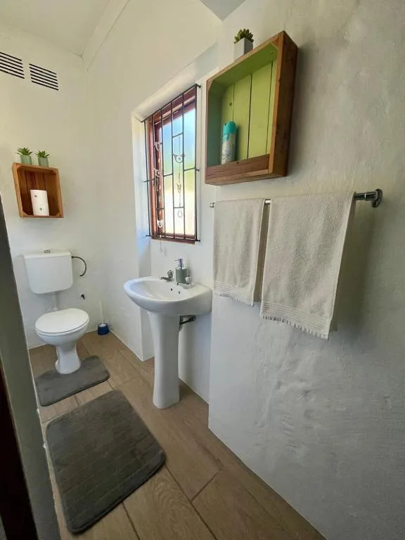 Bright bathroom with pedestal sink, toilet, towel rail, and window