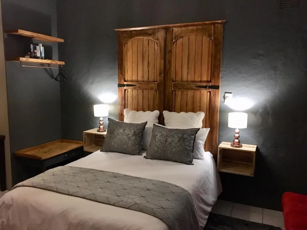 Modern bedroom with wooden headboard, white bedding, and dark accent wall