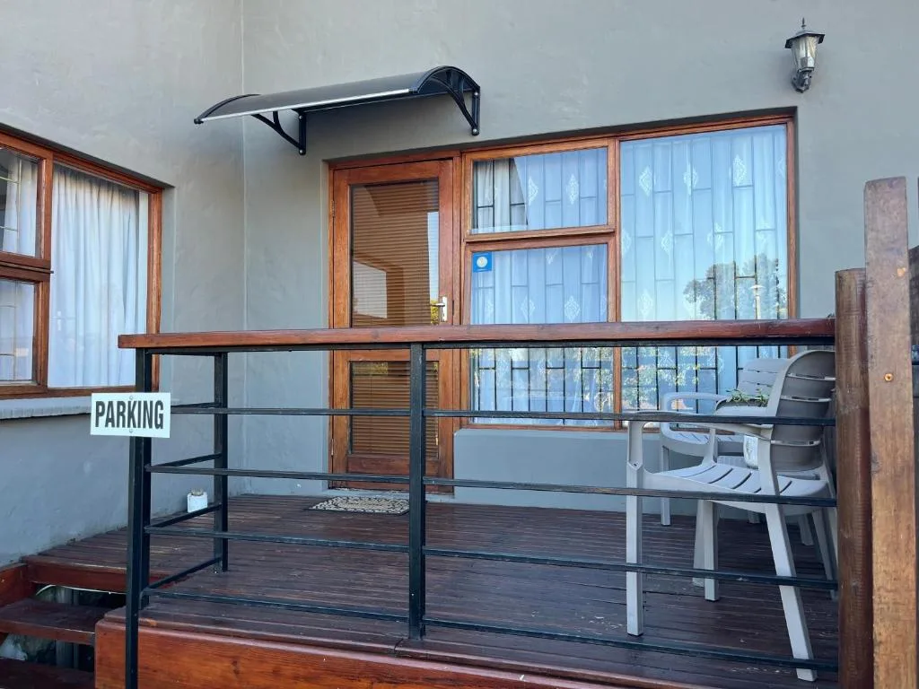 Wooden deck with metal railing and outdoor seating near entrance