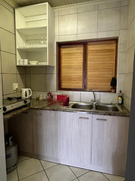 Compact kitchen with granite countertop, double sink, and open shelving