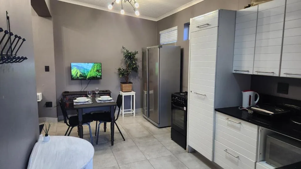 Modern kitchen with stainless steel appliances and white cabinetry, dining area visible