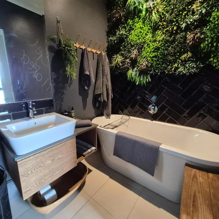 Modern bathroom with freestanding bath, vessel sink, and living plant wall