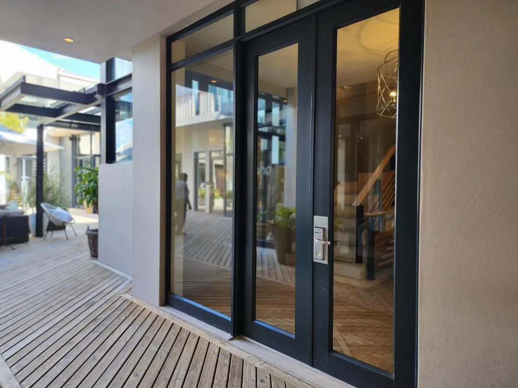 Modern wooden deck with black-framed glass doors opening to interior