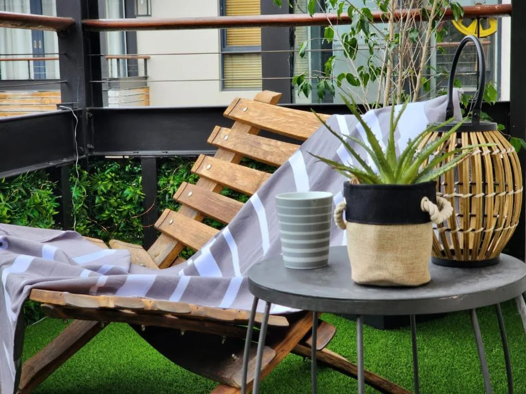Outdoor deck with wooden lounger, potted plants, and modern furnishings