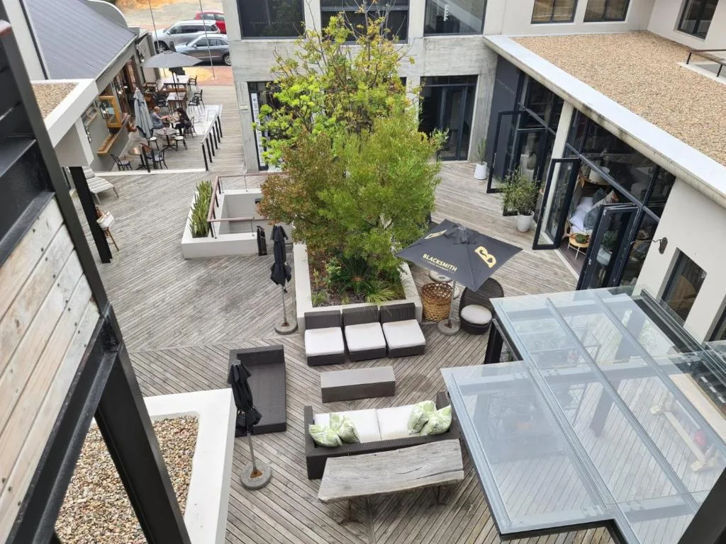 Modern courtyard deck with lounge seating, potted plants, and dining area