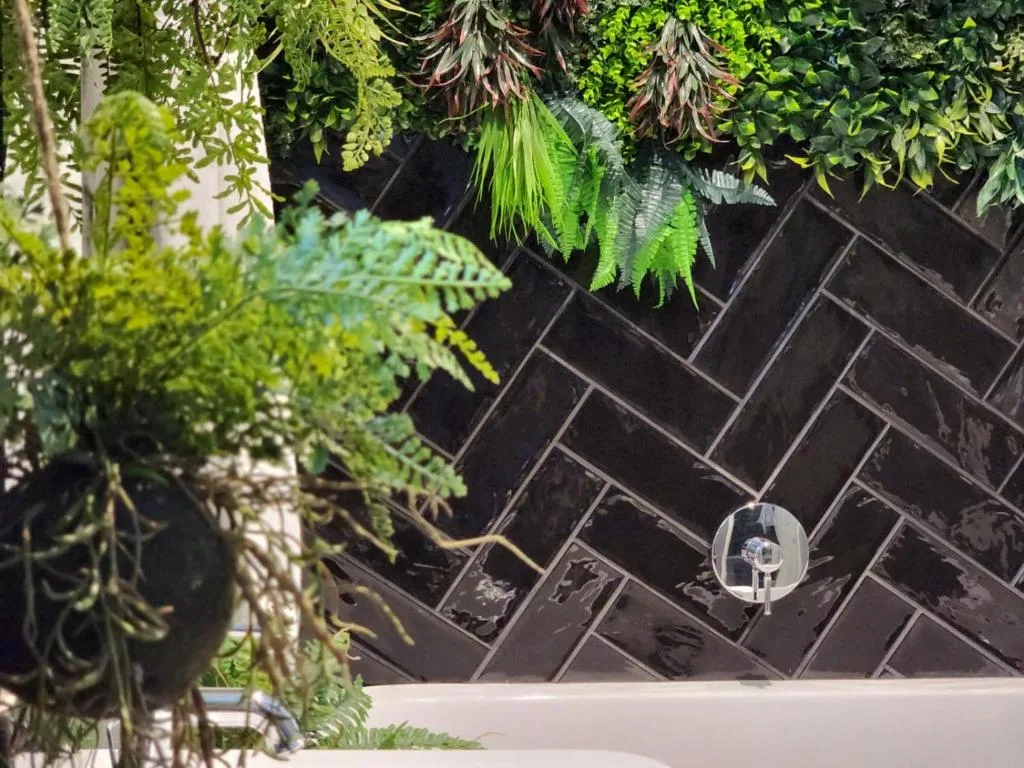 Lush hanging plants and greenery above dark herringbone brick wall detail