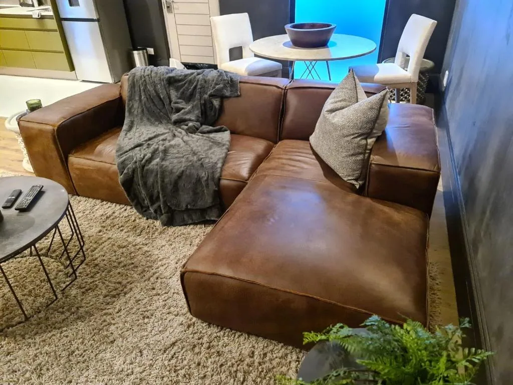 Brown leather sectional sofa with throw blanket and decorative pillows in modern living room
